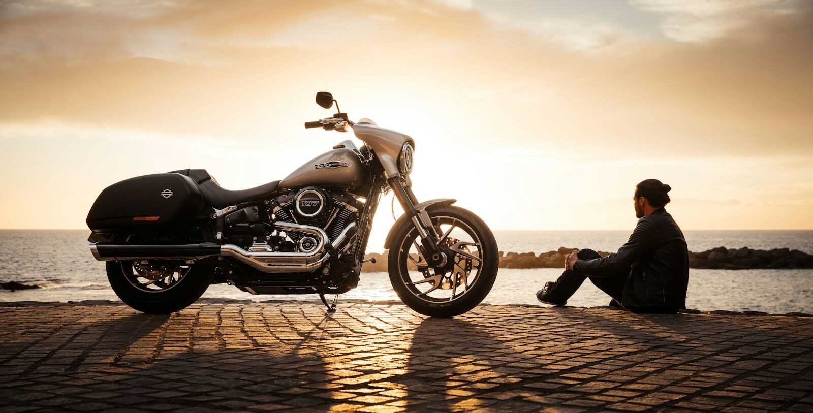 bikes booking man sitting on ground beside parked silver cruiser motorcycle