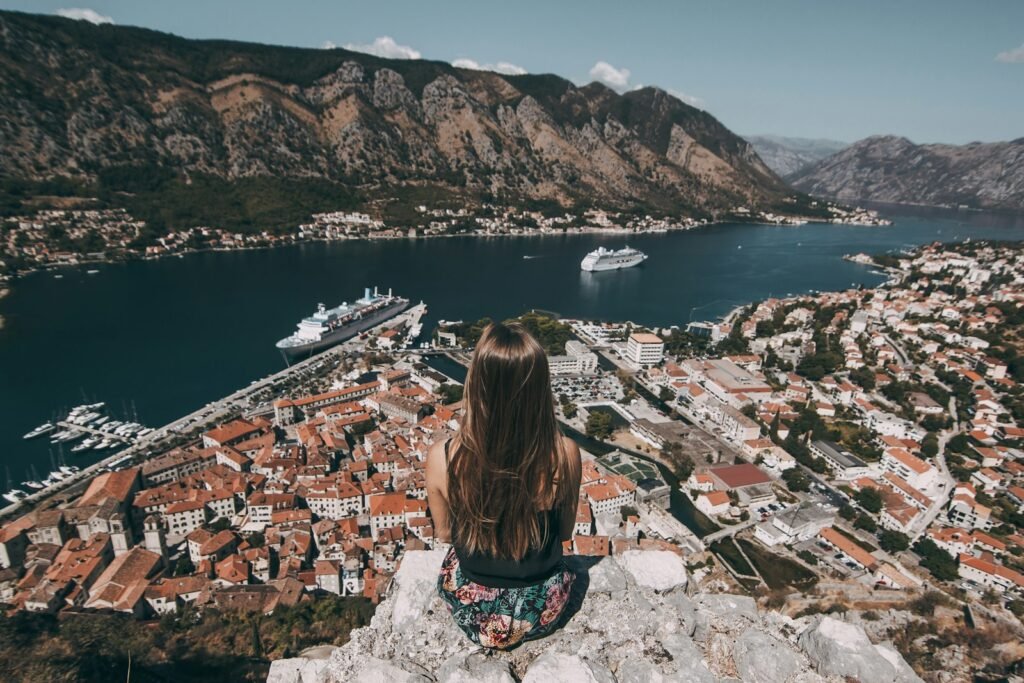 Kotor, Montenegro woman sitting on top of cliff facing buildings