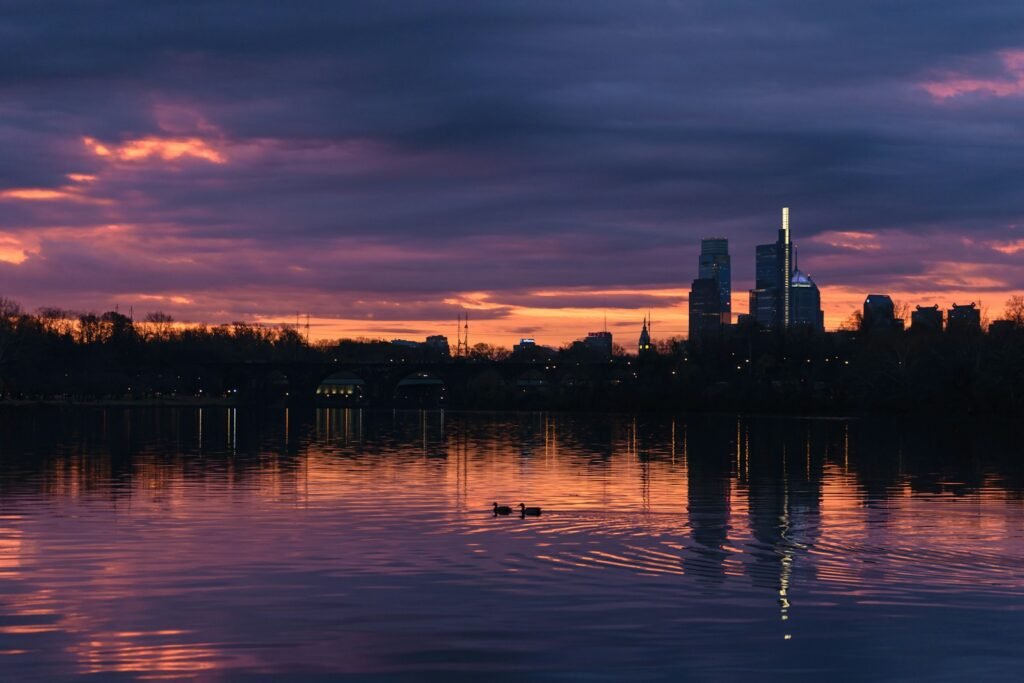 Philadelphia Travel Guide. a beautiful sunset over a lake with a city in the background