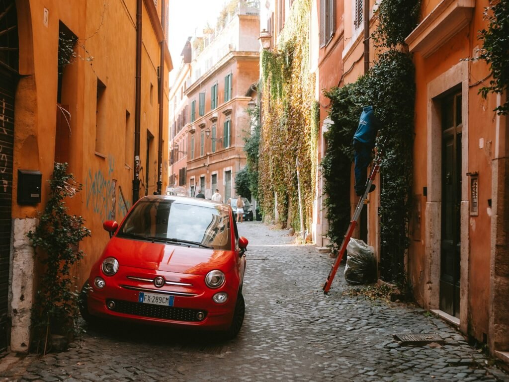 Trastevere A red car is parked on a narrow street
