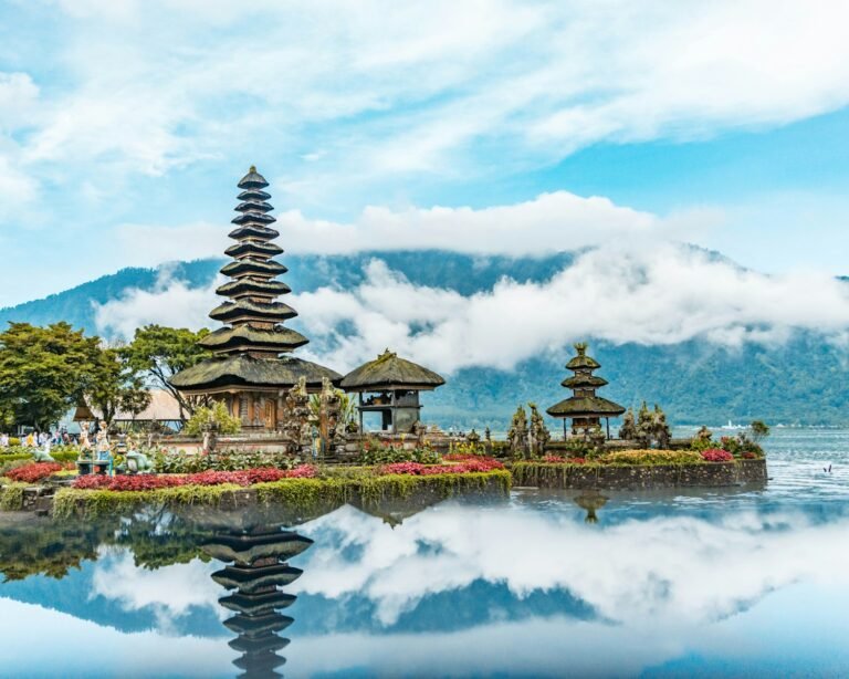 bali travel guide brown and green temple near body of water under blue and white cloudy sky during daytime