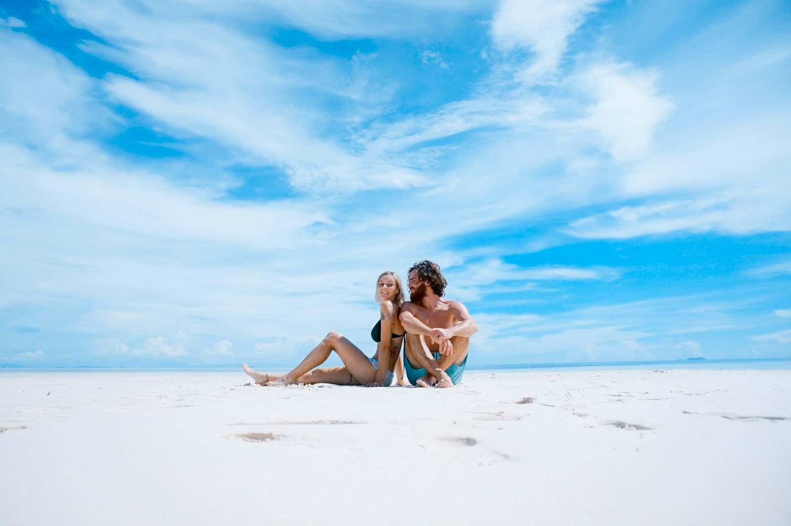 subscribe man sitting beside of woman in black bikini top