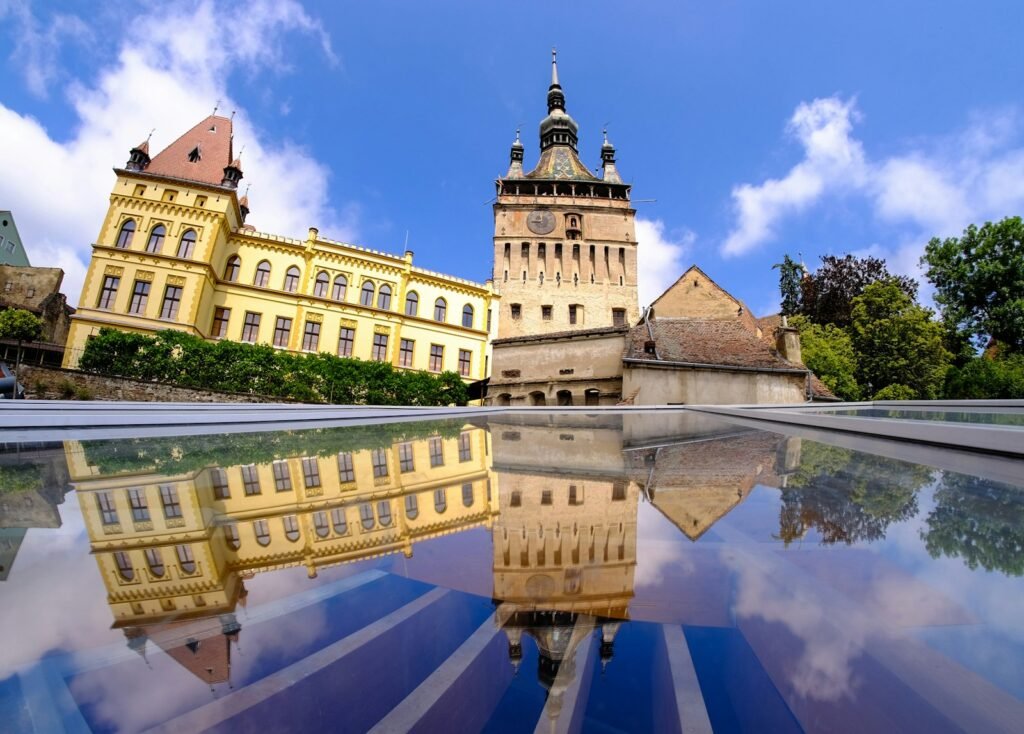 Sighișoara brown concrete building near body of water under blue sky during daytime