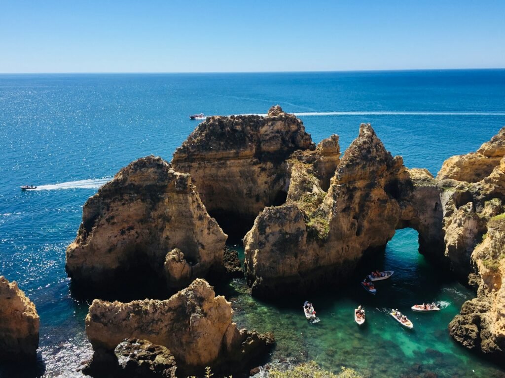 Ponta Da Piedade, Lagos, Portugal people swimming on sea near brown rock formation during daytime