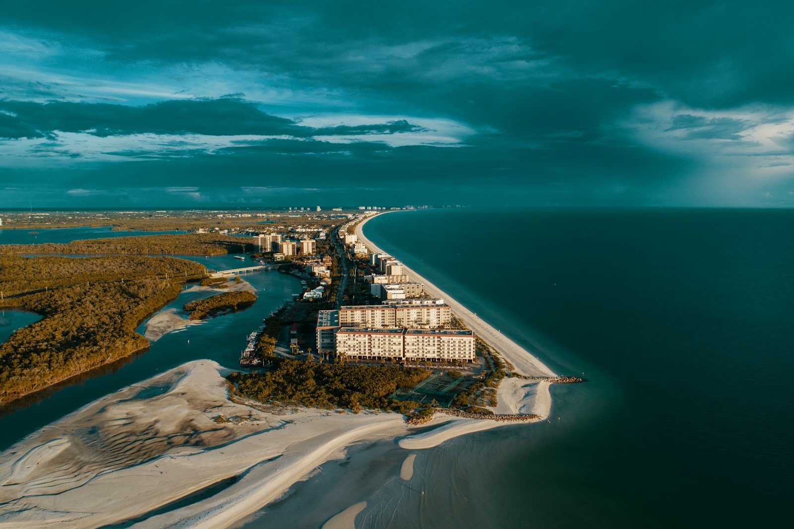 Hotels and Flights aerial photography of white house beside ocean under gray clouds at daytime