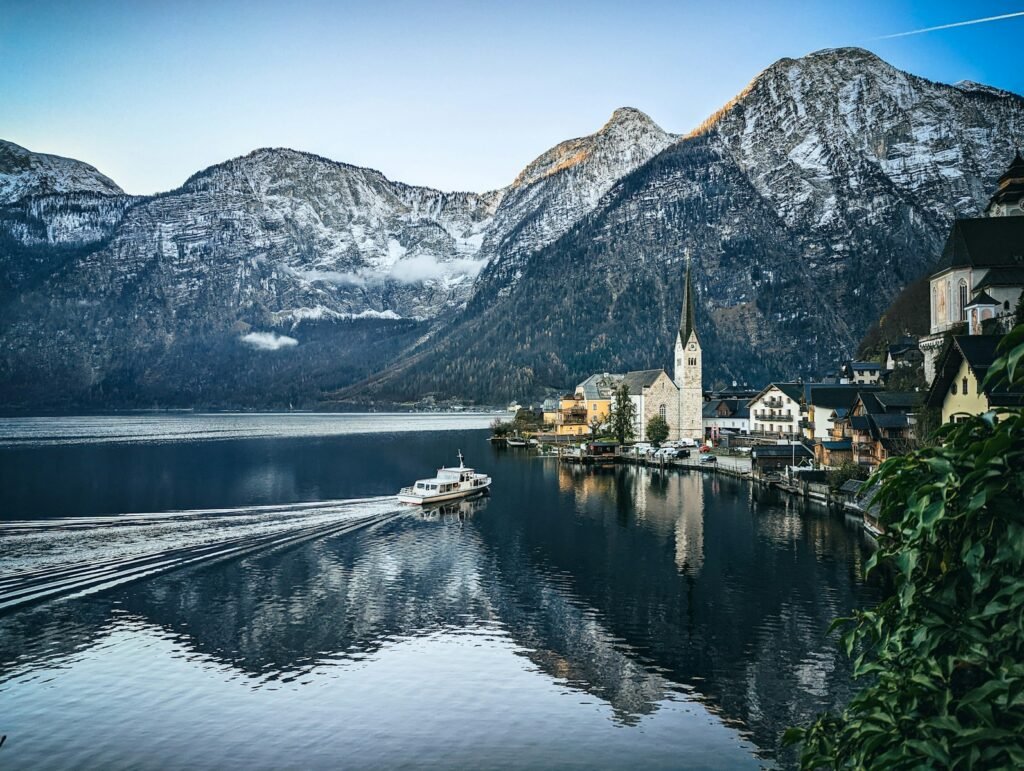 Hallstatt Lake, Austria a boat traveling down a river next to a mountain range